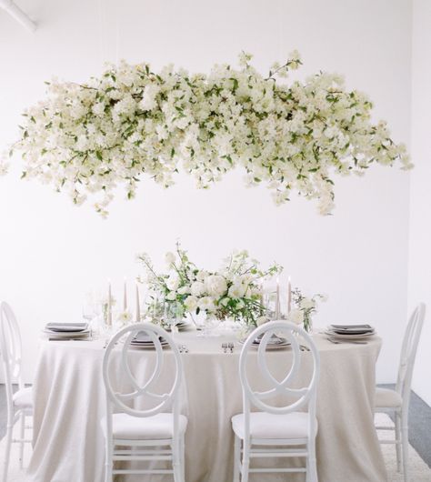 white wedding modern flowers modern white hanging chandelier hanging white flowers hanging cherry blossoms Flower Chandelier Wedding, Cherry Blossom Wedding Decor, Floral Chandelier Wedding, Hanging Flowers Wedding, Tablescape Wedding, Modern Tablescape, Hanging Wedding Decorations, Wedding Chandelier, Cherry Blossom Wedding