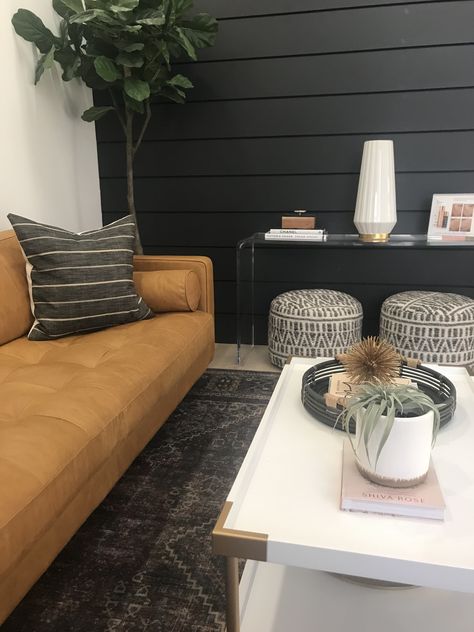 light brown leather couch, dark gray accent wall, and light decor make for a beautiful space Dark Gray Accent Wall, Light Brown Leather Couch, Gray Accent Wall, Beach Apartment Decor, Media Room Paint Colors, Tan Leather Couch, Masculine Living Rooms, Faux Leather Couch, Dark Accent Walls