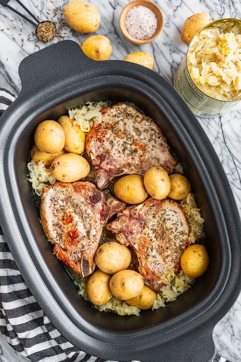 Slow Cooker Pork Chops and Sauerkraut -- made in your crockpot, this easy pork chops and sauerkraut recipe has the traditional flavor you crave without all of the fuss! Uses bone-in pork chops, sauerkraut, and baby yellow potatoes for an all-in-one meal with side dishes included. It's a delicious New Year's tradition passed down by my German-Hungarian great grandmother. | crockpot pork chops and sauerkraut | pork and sauerkraut recipe #porkandsauerkraut #slowcookerrecipes #crockpotrecipes Pork Chop Recipes Crockpot Saurkraut, Saurkraut Recipes Homemade, Pork Chops Sauerkraut, Crockpot Pork And Sauerkraut, Pork And Sauerkraut Recipe, Pork Roast And Sauerkraut, Pork Loin Chops Recipes, Pork Chops And Sauerkraut, Pork And Sauerkraut