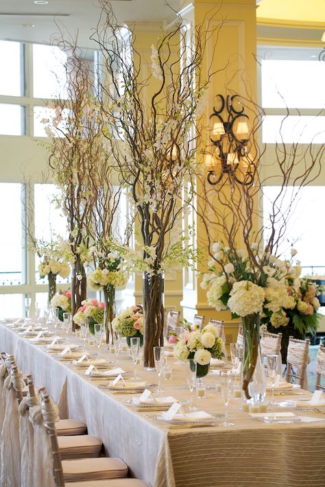 I like the smaller curly willow vases but with different flowers. Bringing the rustic feeling of the outdoors in, however make sure that the flora that you will be using is suitable for the venue. For example I would not recommend this for a stately home as it may take away the attention from the historic detailing.  Notes from De Fantast Curly Willow Wedding, Cylinder Centerpieces, Branch Centerpieces, Hotel Flowers, Corporate Events Decoration, Corporate Flowers, Lighted Branches, Curly Willow, Tree Centerpieces