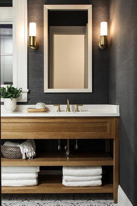 A white beveled mirror contrasts a bathroom wall covered in black grasscloth wallpaper lit by nickel sconces mounted over a beige oak washstand. Grasscloth Wallpaper Bedroom, Wallpaper Accent Wall Bathroom, Wc Decoration, Small Bathroom Wallpaper, Transitional Decor Bathroom, Transitional Bathroom, Wallpaper Accent Wall, Basement Bathroom, Grasscloth Wallpaper