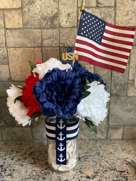 Red, Blue and white flowers arranged in a mason jar with shells inside. American Flag and Us Navy cupcake decorations sticking out top. Blue and white striped ribbon around the mason jars.  Blue ribbon with white Anchor going down jars. Us Navy Centerpiece Ideas, Navy Retirement Party Ideas, Navy Party Themes, Navy Retirement Party, Navy Centerpieces, Navy Bootcamp, Sea Cadets, Navy Retirement, Navy Ball