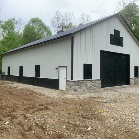 This beautiful pole barn storage building is set back on top of a hill in a secluded wooded area in Central Ohio. The white sidewalls with black trim and stone wainscot on the front of the building really make the building shine. The custom 4-sided cupola on top of the building provides for a source of natural lighting inside the building.   The building is 42' x 64' with over 14' in height for storage of an RV, boat, trailers and other toys. Pole Barn For Boat Storage, White And Black Metal Building, White Metal Shop With Black Trim, White Metal Shop Building, White And Black Metal Shop, White Shop With Black Trim, White Shed House, White Metal Building With Black Trim, Black And White Shop House