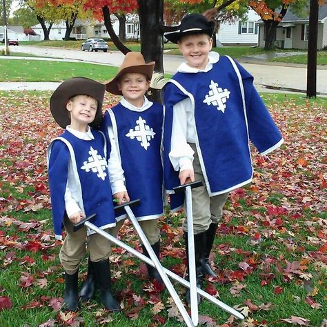 Three Musketeers. Literary Halloween costumes 1. Blue felt tunic 2. White felt cross. Google image, "musketeer cross" 3. Chinos, white dress shirts, and boots- Salvation Army thrift store. 4. Sew-ology double fold quilt binding bias tape, silver metallic. Hobby Lobby 4. Hobby Lobby feathers 3 Musketeers Costume, Three Musketeers Costume, Musketeer Outfit, Musketeers Costume, Kids Book Character Costumes, Felt Cross, Musketeer Costume, Toddler Boy Costumes, Book Character Costumes