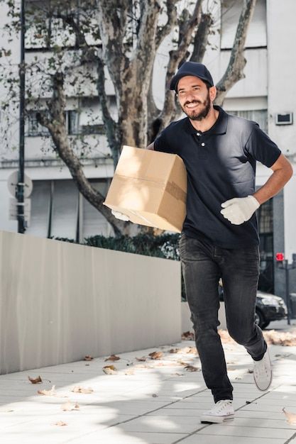 Smiling delivery man running on pavement... | Free Photo #Freepik #freephoto #delivery-man #post-man #delivery-person #package-delivery Delivery Man Photography, Man Photography, Special Clothes, Happy Labor Day, Red Hats, Wearing Red, Man Running, Feeling Happy, Delivery Man