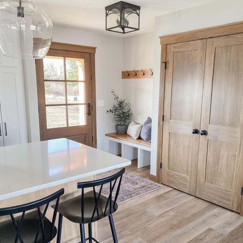 This rustic farmhouse kitchen features white walls with light wood doors. Coordinating light wood interior door trim frames the doors providing balance and visual grounding. Bright natural light from a light wood windowpane door fills the room and light wood flooring runs throughout. Light Wood Doors, White Trim With Wood Doors, Wood Doors White Trim, Light Wood Interior, Light Wood Flooring, Natural Wood Trim, Wood Interior Door, Interior Door Trim, Farmhouse White