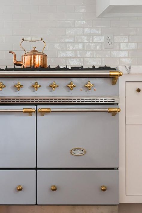 A stunning gray Lacanche stove accented with a brass trim sits against white subway backsplash tiles beside white cabinets topped with a honed white marble countertop. Lacanche Stove, Nantucket Interior Design, French Farmhouse Kitchen, Kitchen Remodel Countertops, Kitchen Countertop Materials, Brass Trim, Cottage Kitchens, White Marble Countertops, Home Luxury