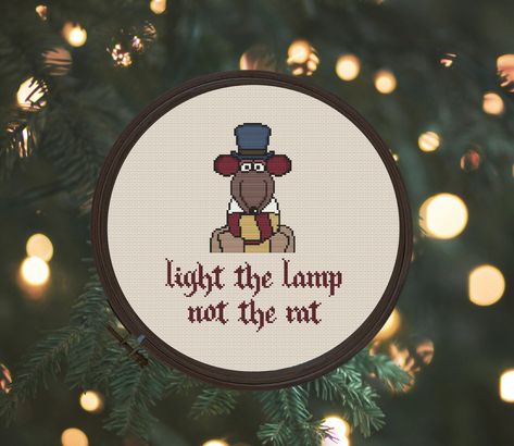 "Light the lamp not the rat cross stitch pattern This is a digital item, you will not receive the finished item, it is to create yourself. The PDF file of the pattern will be available for instant download once payment is confirmed. PDF PATTERN INCLUDES ◊ Color photo of finished stitch ◊ Easy-to-read, full-color chart ◊ List of DMC thread colors PATTERN DETAILS ◊ Fabric used in the picture: Aida 14 count  ◊ Stitch count: 95 stitches wide and 113 stitches tall ◊ DMC color count: 13 ◊ Finished siz Rat Cross Stitch, Christmas Cross Stitch Patterns, Geek Christmas, Cross Stitch Quotes, A Christmas Carol, Thread Colors, Cross Stitch Patterns Christmas, Dmc Thread, Charles Dickens