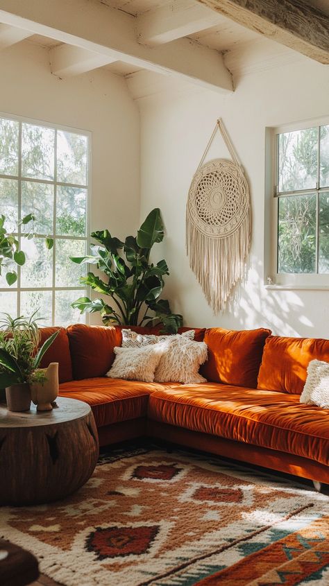 Boho living room with orange velvet sofa, wooden beams, macrame wall art, plants, and colorful geometric carpet. Warm Mid Century Sofa Living Room, Boho Mid Century Modern Living Room, Inviting Home Decor, Maximalist Boho, Orange Couch, Boho Living Room Ideas, Velvet Corner Sofa, Boho Mid Century Modern, Modern Living Room Ideas