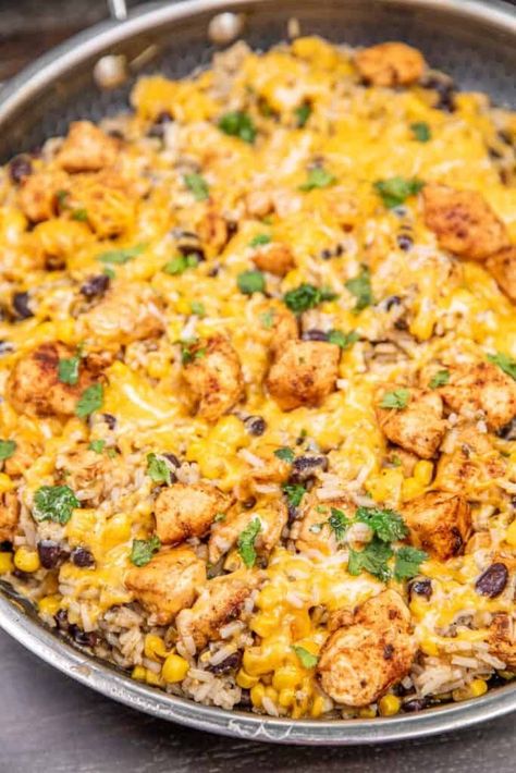 Cheesy Mexican Chicken and Rice Recipe - Tender chicken seasoned with taco spices, black beans, corn instant rice, and salsa verde come together in a skillet for a hearty, one-pan meal. Topped with melted cheese and garnished with fresh cilantro, this dish is bursting with vibrant flavors. Perfect for a family meal or meal prep! Chicken Cheese And Rice Mexican Recipe, Cheesy Mexican Chicken And Rice, Cheesy Mexican Chicken, Slow Cooked Chicken Breast, Chicken Rice Beans, Taco Spices, Cheesy Mexican Rice, Chicken Rice Skillet, Mexican Chicken And Rice