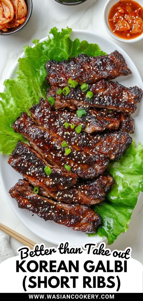 A plate of Galbi, Korean short ribs, beautifully grilled and glazed, garnished with sesame seeds and green onions, served on a bed of fresh lettuce leaves, accompanied by kimchi for a flavorful and traditional Korean dish. Asian Rib Recipes, Short Rib Korean Bbq, Korean Short Rib Marinade, Korean Bbq Ribs Slow Cooker, Beef Braising Ribs Recipe, Short Ribs Recipe Korean Style, Korean Bbq Short Ribs Recipes, Korean Ribs Marinade, Korean Short Ribs Marinade