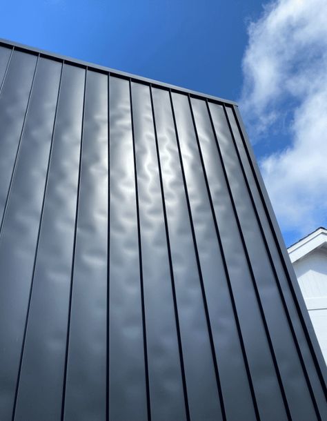 What is Oil Canning? Causes + Solutions For A Common Metal Roof Problem Grey Steel Roof, Roof Panels Ideas, Black Standing Seam Metal Roof, Metal Siding Ideas Exterior, Matte Black Metal Roof, Metal Roofs On Houses, Metal Roofing Fence, Charcoal Metal Roof, Metal Roofing Ideas