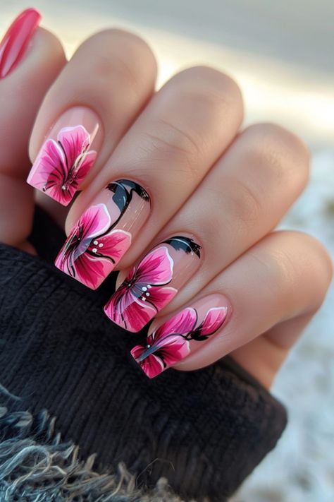 Hand with manicured nails featuring pink flower designs. Nail Designs With Hibiscus Flowers, Nail Designs Hibiscus Flower, Tropical Nail Art Hawaii, Summer Nails 2024 Hibiscus, Hibiscus Flower Nail Art, Hibiscus Flower Toe Nails, 2025 Nails, Hibiscus Flower Nail, Hibiscus Flower Nails 2000s