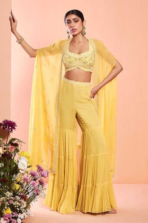 Buy #daisy #yellow embroidered cape with scallop hem. Paired with dabka embroidered blouse and tiered sharara by #NiamhbyKriti at #AzaFashions Shop online now at #Azafashions.com Call +91 8291990059 or email contactus@azafashions.com for enquiries. #wedding #festive #ethnic #tradional #shopping #shoponline #party #reception #bride Women Haldi Outfit, Yellow Indian Outfit, Cape Sharara, Yellow Sharara, Sharara Designs, Beaded Cape, Embroidered Cape, Daisy Yellow, Pearl Work