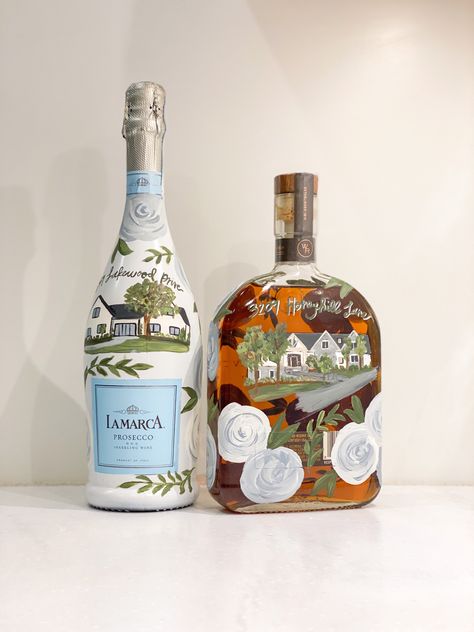 La marca prosecco and Woodford reserve bottle with homes painted on them Painted Champagne Bottle Housewarming, Painting On Alcohol Bottle, Paint Liquor Bottles Diy, Painted Woodford Reserve Bottle, Painted La Marca Bottle, Bourbon Bottle Painting, Painted Liquor Bottles Diy, Painted Bourbon Bottle, Wedding Painted Champagne Bottle