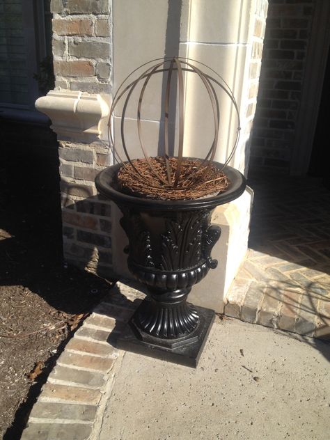 Finally a way to fill my urns in the winter. A metal orb and grapevine wreath. Weighted down with a brick. Metal Orbs In Planters, Porch Pots Winter, Porch Pots Ideas, Winter Outdoor Planter Ideas, Rusty Decor, Winter Planters Front Porches, Winter Porch Pots, Porch Urns, Winter Planter Ideas