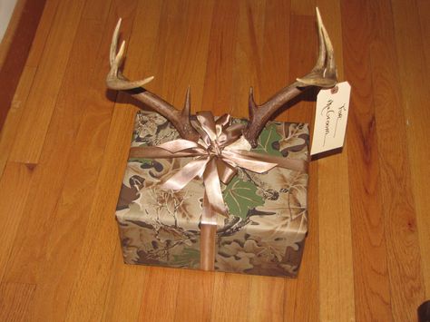 a book on hunting for the groom wrapped in camo. gift wrap with brown ribbon and deer antlers. Gifts For Hunting Boyfriend, Christmas Gifts For Country Boyfriend, Hunting Gift Basket, Hunting Gifts For Boyfriend, Basket For Boyfriend, Camo Decor, Hunting Gifts For Men, Camo Gifts, Christmas Ideas For Boyfriend