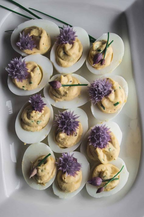 Classic deviled eggs are elevated with truffle oil and fresh chives. Garnished with blossoms from the chive plant for an elegant look. Elevated Deviled Eggs, Chive Blossom Recipe, Christmas Deviled Eggs Ideas, Elevated Appetizers, Fancy Side Dishes, Best Appetizers For Parties, Truffle Deviled Eggs, Fancy Deviled Eggs, Chive Plant