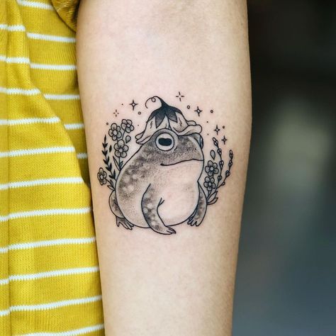 Leah Samuels on Instagram: “Cottagecore bb on @craftmyspirit 🌿 Done at @howdy.la . . . . . . #toad #toadtattoo #cutetattoo #cottagecore #delicatetattoo…” Cottage Tattoo Simple, Frog With Flower Tattoo, Frog Tattoo Flower, Flower Frog Tattoo, Fairy Cottage Tattoo, Small Toad Tattoo, Witch Frog Tattoo, Cottagecore Sleeve Tattoo, Fairy Frog Tattoo