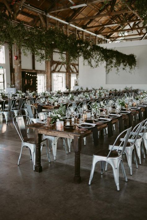 Metal chairs, draped greenery, and farmhouse tables create a industrial yet cozy feel | Image by Daring Wanderer Loft Wedding Reception, Shed Wedding, Wedding Table Designs, Brewery Wedding, Loft Wedding, Warehouse Wedding, Farmhouse Wedding, Tables And Chairs, Vancouver Wedding