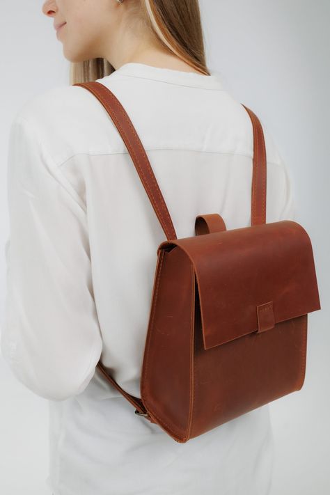 Meet a minimalistic backpack - a stylish accessory for women.💼 It's a medium-sized, leather backpack with a modern design. It features adjustable shoulder straps and a secure flap closure with a magnetic clasp. The backpack's sleek appearance is complemented by its leather finish, and it does not have any external pockets or additional compartments, which gives it a clean and elegant look. It's a versatile piece that could be paired with casual attire for a chic, functional accessory. The inter Mini Backpack Outfit, Minimalistic Backpack, Leather Backpack Women, Small Leather Backpack, Handmade Backpack, Handmade Backpacks, City Backpack, Backpack For Women, Purse Backpack