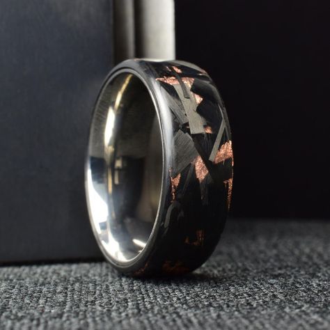 Handcrafted in-house, this Chopped Carbon Fiber is combined with Genuine Copper to create a stunning and durable ring. The Titanium liner is a light-weight metal with a mirror polish. Not only is this ring stylish, but it is also incredibly sturdy and designed to last. The intricate design and attention to detail make this ring a true work of art that you will cherish forever Forged Carbon Fiber, Carbon Fiber Rings, Artisan Rings, Black Ring, Ring Displays, Intricate Design, Mens Wedding Bands, Black Rings, Metal Rings