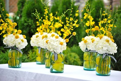 Yellow orchids, billy buttons, and oranges add cheer to mason jar centerpieces. Yellow Orchids Centerpiece, Craspedia Globosa, Yellow Wedding Centerpieces, Lemon Decorations, Yellow Centerpieces, Wooden Backdrops, Baby Shower Table Decorations, Yellow Orchid, Billy Buttons