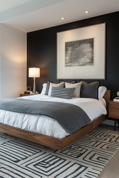 Modern bedroom with a black accent wall behind the bed, featuring a large framed artwork, bedside tables, and soft lighting, emphasizing sleek decor. Small Masculine Bedroom, Accent Walls Bedroom, Dark Modern Bedroom, Charcoal Bedroom, Brown Accent Wall, Male Bedroom Ideas, Dark Accent Walls, Black Accent Walls, Modern Bedroom Ideas