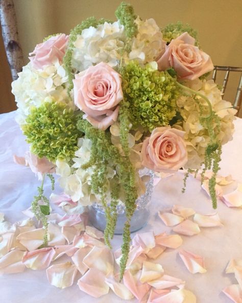 Simply elegant wedding arrangement.  Short cylinder vase with green hydrangeas soft pink roses , white hydrangeas with green hanging amaranthus . Pink White Gold Flower Arrangement, Pink Green Centerpiece, Pink And Green Hydrangea Centerpiece, Green And Pink Floral Arrangements, Pink And Green Flower Centerpieces, Pink Green Silver Party Decor, Pink And Green Wedding Centerpieces, Pink And Green Garden Party, Light Pink And Light Green Wedding