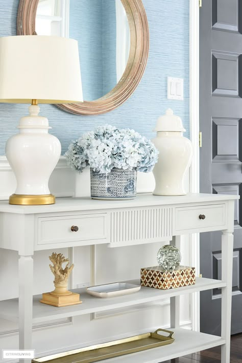 Beautiful entryway spring decor with blue and white accessories styled on a classic console table. This is such a fresh look on a traditional blue and white setting. Coastal Entryway Table Decor, Blue And White Console Table Decor, White Foyer Table, Coastal Grandmother Entryway, Blue And White Buffet Decor, White Entryway Table Decor, White Entry Table Decor, White Sideboard Decor, Blue Console Table Entryway