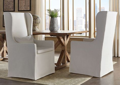 Decorate your space with the statement Richland Wingback Chair with slip cover. This linen look chair has roomy seating that includes a loose pillow. Choose to have your chair with exposed rubberwood legs or go for a more luxurious look with the alternative slip cover. | Richland Wingback Dining Chair W/ White Slipcover White Slipcover, Wingback Chair Slipcovers, Modern Wingback Chairs, Slipcovered Chair, White Slipcovers, Wingback Dining Chair, Host Chairs, Bedside Table Design, Dining Chair Slipcovers