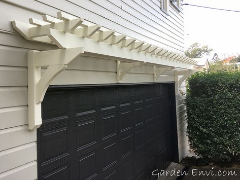 This small white Eyebrow Pergola creates a focal point above the garage door softening the exterior of the side of the house.   With no visible fixings it makes a great features for this Queenslander residence in Indooroopilly, Brisbane. #hamtponsstyle #hamptonsperogla #queenslanderhouses Garage Eyebrow Pergola, Eyebrow Pergola Garage Doors, Garage Eyebrow, Pergola Over Garage, Eyebrow Pergola, Garage Arbor, Rock Exterior, Door Portico, Garage Trellis