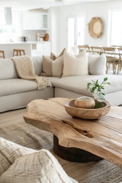 A cozy, well-lit living room with a large beige sofa filled with throw pillows, a rustic wooden coffee table, and a dining area in the background. Organic Modern Living Room, Modern Organic Home, Organic Living Room, Earthy Living Room, Minimalist Living Room Design, Earthy Hues, Natural Living Room, Neutral Living Room, Organic Forms