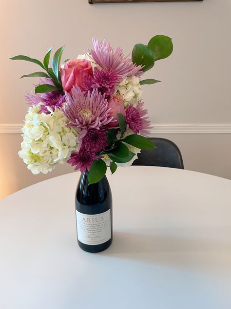 Centerpiece Wine Bottle, Flower Arrangement On Top Of Wine Bottle, Wine With Flowers On Top, Flower Bouquet On Wine Bottle, Flower Bouquet With Wine Bottle, Wine Bottle Floral Bouquet, Champagne Bottle Flowers Bouquet, Wine Bottles With Flowers, Floral Wine Bottle