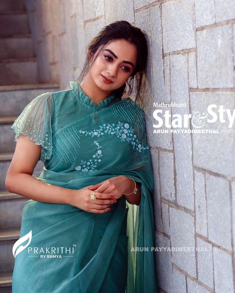 In a teal color saree and sheer high neck cape / cap sleeve blouse design Indian Blouse Designs, Blouse Designs High Neck, Blouse Designs Catalogue, Saree Blouse Neck Designs, New Saree Blouse Designs, Fashionable Saree Blouse Designs, Blouse Back Neck Designs, Blouse Design Images, New Blouse Designs