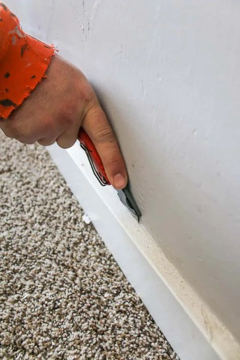 Using a utility knife, score the caulk from along the top seam where the baseboard meets the drywall. If you skip this step, you risk tearing the drywall as you remove the board. Make sure to cut along the complete length of the baseboard parallel with the wall so the board will easily detach from the wall in the next steps. Then, using a putty knife, slide the knife the length of the wall between the wall and the baseboard to loosen any remaining caulk or glue that has been used to affix the ba Remove Baseboards, Flooring On Concrete, Install Laminate Flooring, Removing Baseboards, Wood Baseboard, Installing Laminate Flooring, Baseboard Trim, Skirting Boards, Nails And Screws