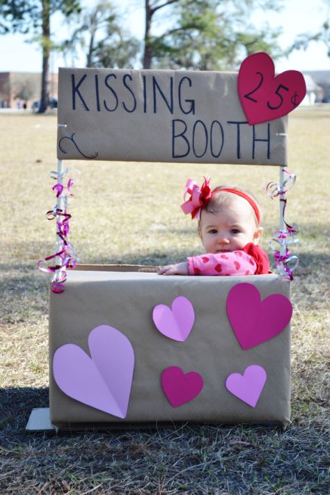 I put together a 'kissing booth' for my daughter's Valentine Day pictures. I made the box from a cardboard box, wooden rod, wrapping paper, scrapbook paper, and curling ribbon. Easy Peesy! Baby Kissing Booth Valentines Day, Valentine's Day Pictures Kids, Diy Kissing Booth Cardboard, Kissing Booth Photoshoot, Valentines Baby Photoshoot, Valentines Photo Booth, Girls Valentines Boxes, Valentine Mini Session, Valentines For Daughter