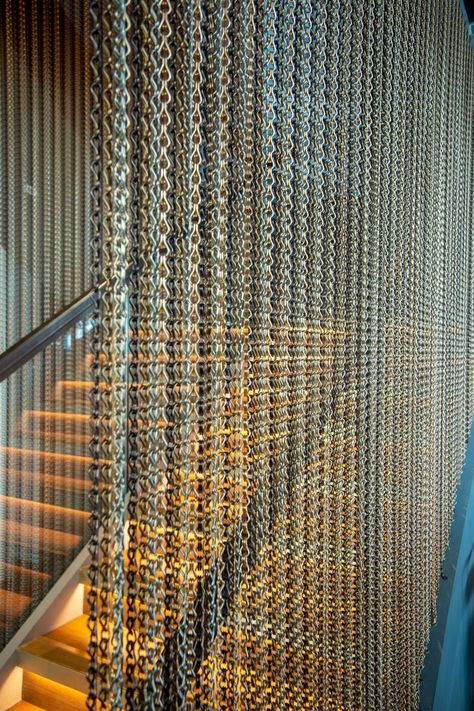 Working closely with WFC Contractors Ltd, we were asked to specify a suitable metal to go alongside the glass bannister by the staircase. To achieve the desired look, we supplied our Kriskadecor chains for either side of the staircase. These were finished in Coffee 20221, Brown 20206, Sand 20228, and Apricot 20220. Each chain from left to right was finished in a different colour, in vertical stripes to give the curtain a textured look. Metal Chain Curtain, Glass Bannister, Chain Curtain, Luxury Retail Store, String Curtains, Glass Curtain, Space Dividers, Stair Handrail, Flower Installation