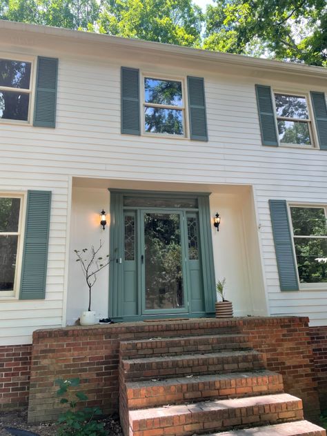 White House Teal Trim, White Home Green Shutters, Yellow House Green Shutters, White House With Colored Shutters, Cream House Green Trim, Painted Shutters On White House, White House With Sage Green Shutters, Cream House Green Shutters, White House With Green Door