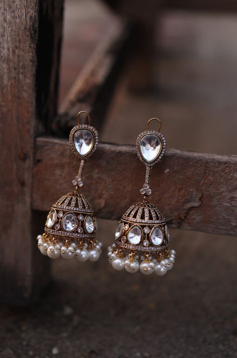 Illuminate your style with our Victorian Polki Jhumka Earrings, designed to radiate light and glamour. Embellished with reflective polkis, these earrings evoke the enchanting atmosphere of a starlit night, with a subtle shimmer that adds a touch of sparkle to any room. Perfect for adding a touch of elegance and sophistication to your look, these earrings are a must-have accessory for any occasion. Finish: 22KT Gold Plating Material: Silver, Copper Alloy, Polki, Pearls Color: Gold Size: One Size Polki Jhumkas, Desi Earrings, Pearl Jhumkas, Traditional Jhumka, Radiate Light, Starlit Night, Silver Jhumkas, Hand Jewelry Rings, Jhumka Designs