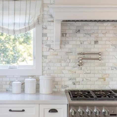 Calcutta gold marble beveled brick backsplash tiles in a transitional kitchen combined with white shaker cabinets, light gray quartz countertops and a white wood panel range hood. Oil rubbed bronze handles and pulls accent the cabinets with the perfect contrast in a popular hardware choice.  Design by Fletcher Rhodes  #kitchenbacksplash #backsplashtile #tilebacksplash #backsplashtile #calcuttagold #calcuttagoldmarble #tilework #tilelove #tileshop #tiledesign #tileart #tileinspo #tileinspiration Light Gray Quartz Countertops, White Brick Backsplash, Brick Tile Backsplash, Kitchen Cabinets And Backsplash, Backsplash Kitchen White Cabinets, White Wood Paneling, Beveled Subway Tile, Cabinet Pantry, White Shaker Cabinets