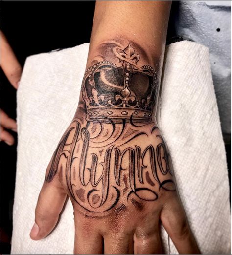 Amazing artist Jorge Jamaica @jamaica.tatts awesome crown hand script tattoo! #jorgejamaica #jorge #jamaica  #renaissance  #ink #3d  #tattoos #tattoo  #amazing  #lettering  #portraits #arm #blackandgrey #crowntattoo #scripttattoo #photorealism #crown  #amazing  #la #handtattoo #hand #fresh #calligraphy #art #artwork #europe #portrait  #script #west Crown Hand Tattoo Men, Hand Tattoo Name, Hand Script Tattoo, Name Tattoos On Hand, Name Hand Tattoos, Crown Tattoo On Hand, King Crown Hand Tattoo, Men’s Crown Tattoo, King Crown Finger Tattoo