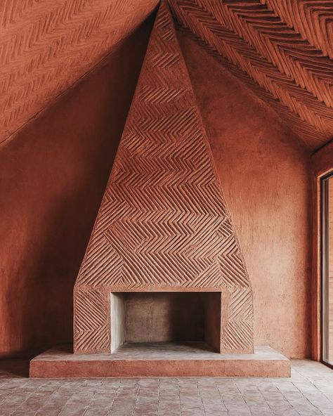 This striking fireplace creates a mood of warmth and calm, combining earthy textures with bold geometric patterns. The herringbone carvings on the terracotta-toned surface give the space a handcrafted, timeless quality. It evokes a sense of grounded tranquillity, while the minimalist design and natural materials strike a balance between rustic charm and modern sophistication. Photography by @jeanjacquesbalzac #interiordesign #fireplace #architecture #minimalist #earthy #modernrustic #natur... Terracotta Fireplace, Fireplace Design, Apartment Interior, Restaurant Design, Modern Rustic, Architecture Details, Rustic Charm, Design Details, Minimalist Design