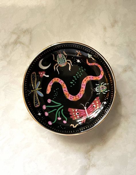 Our ceramic trinket dishes are the perfect catchall for your nightstand or dresser. White ceramic is adorned with our colorful, hand-painted designs, and we lined the edge in metallic gold for added flair. Perfectly packaged in plastic-free gift boxes, pretty enough to give without wrapping! • 3.75″ ROUND DISH • CERAMIC WITH GOLD DETAILING • PLASTIC-FREE GIFT BOX Ceramic Trinket Dish, Dresser White, Color Me Mine, Dish Ceramic, Midnight Garden, Hand Painted Pottery, Mini Frames, Ornament Frame, Holiday Earring