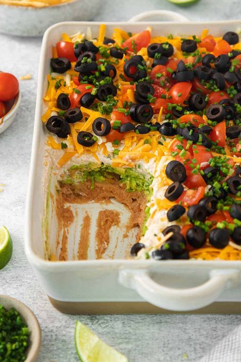 7-layer taco dip in a baking dish with a portion scooped out Seven Layered Dip, Best 7 Layer Dip Recipe, 7 Layer Dip With Ground Beef, 7 Layer Dip Mexican, Dip Crockpot, Layer Taco Dip, 7 Layer Bean Dip, 7 Layer Taco Dip, 7 Layer Dip Recipe