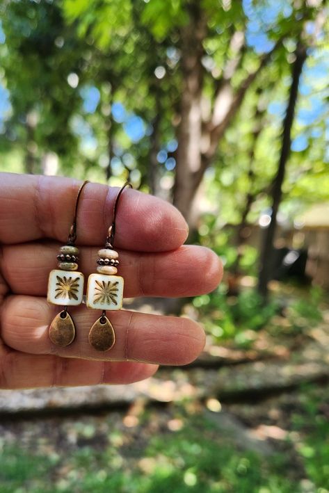 Recent buyer described these earrings as "stunning." The centerpiece for these boho earrings is an Alabaster white tile bead with a gorgeous starburst.  Another petite pair of earrings! Simply gorgeous Czech glass! Love the look! These unique beauties are just under two inches in length, including the copper hooks.  The square tile beads are accented with a stack of luscious mossy green disc beads interspersed with a copper bead.  The whole design is finished off with a lovely dangling copper te Earth Tone Earrings, Dopamine Activities, Starburst Tile, Tile Earrings, Artsy Jewelry, Alabaster White, Rustic Earrings, Dangle Earrings Boho, Mossy Green