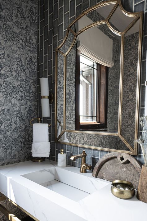 Providing a serendipitous mix of charm and glamor, this powder room showcases a textured tile accent wall paired with a delicate fine line floral wallpaper. The smokey blue color palette contrasts beautifully with the marble vanity and brushed gold accents. Warmth was added to the space using rustic woods accessories, deep stained trim and dried star flower stems. Powder Room With Wallpaper, Tile Powder Room, Room With Wallpaper, Fine Line Floral, Tile Accent Wall, Textured Tile, Stained Trim, Powder Bathroom, Powder Room Wallpaper