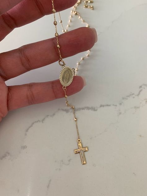 This 14K yellow gold rosary necklace is the perfect religious symbol of faith. Featuring a cross pendant, shiny diamond cut 2.5mm round beads, and a 20” chain, this necklace is a meaningful piece of Catholic jewelry. Its delicate design makes it an ideal gift for anniversaries, confirmations, 1st communion and other special occasions. ♦ Materials: 14K Solid Gold♦ Available colors: Gold ♦ Necklace measurements: 20" total length, beads are 2.5MM♦ Beads measurements: Beads are 2.5MM---------------- Catholic Gold Jewelry, Catholic Cross Necklace, Gold Rosary Necklace, Drops Necklace, Necklace Measurements, Choker Necklace Gold, Catholic Necklace, Beaded Rosary, Gold Rosary