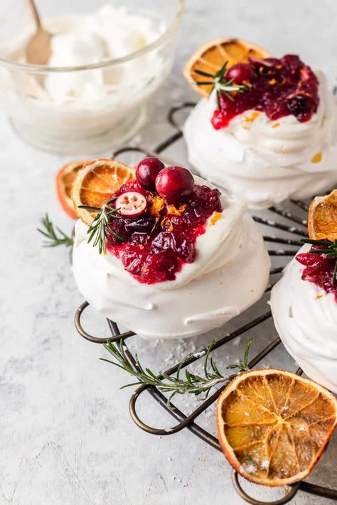 Mini Cranberry Pavlovas combine the crisp outer layer with a soft chewy centre. The meringue is topped with a lightly whipped cream and orange infused cranberry sauce, Light, delicate, crisp, soft, sweet and tangy encapsulate this festive, holiday dessert. By Emma Duckworth Bakes. Cranberry Meringue, Meringue Nests, Mini Pavlovas, Mini Meringues, Cranberry Orange Sauce, Baked Meringue, Mini Pavlova, Cranberry Cream Cheese, Pavlova Recipe