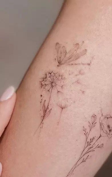 What Do Dandelion Tattoos Mean? Is It For You? Dandelion Dragonfly Tattoo Design, Dandelion Tattoo On Leg, Tattoos That Arent Flowers, Dragonfly And Dandelion Tattoo Design, Dandelion Tattoo With Dragonflies, Dandelion Forearm Tattoo Women, Feminine Dragonfly Tattoo For Women, Fine Line Horizontal Tattoo, Two Dandelion Tattoo